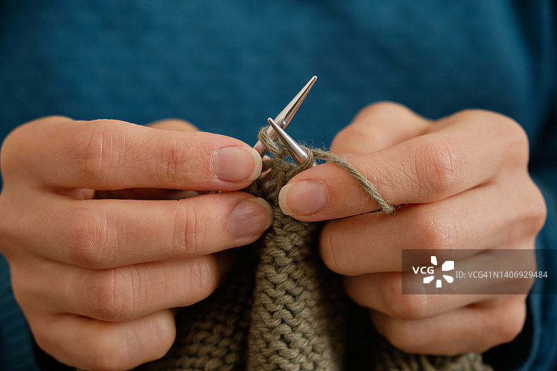 特写：女孩拿着针织品和金属针，在家编织羊毛衫，爱好创意手工概念图片素材