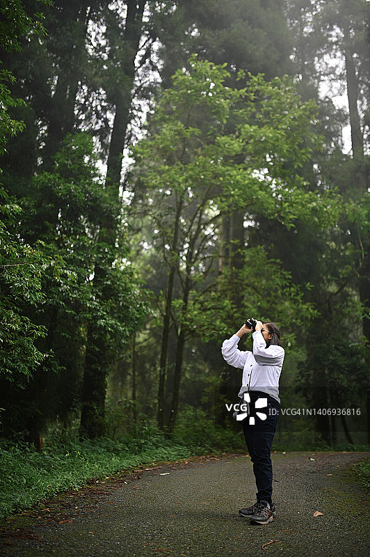 少女在公园里用双筒望远镜观察图片素材