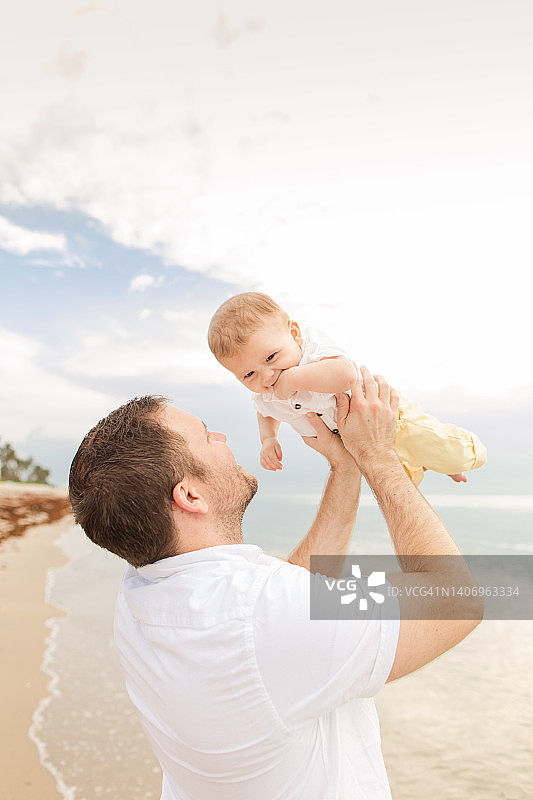 一位31岁的美国父亲在2022年6月日出时分,在佛罗里达州棕榈滩的沙滩上抱着他6个月大的古巴裔美国儿子图片素材