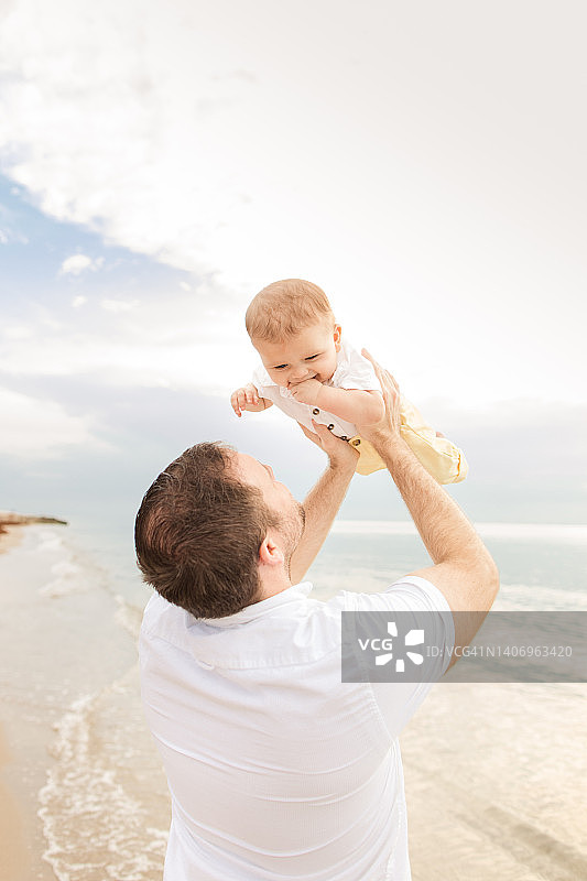 一位31岁的美国父亲在2022年6月日出时分，在佛罗里达州棕榈滩的沙滩上抱着他6个月大的古巴裔美国儿子图片素材