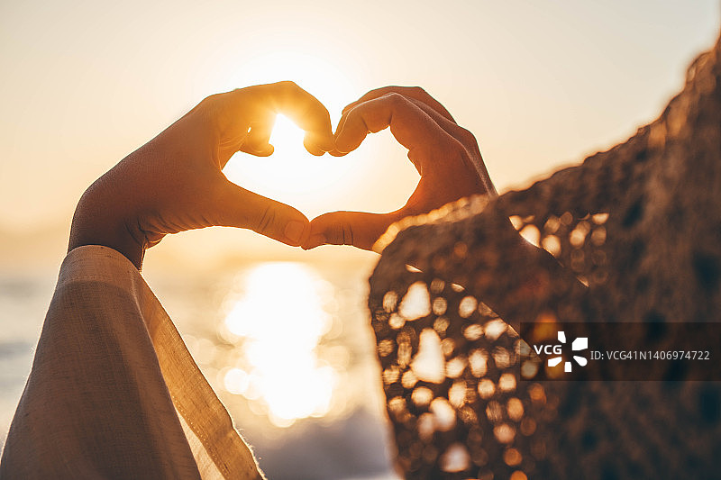 海上日落时分，双手剪影比心图片素材