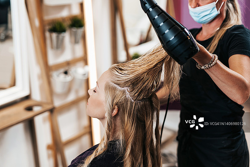 在美发沙龙接受护理的戴防护面罩的女人图片素材