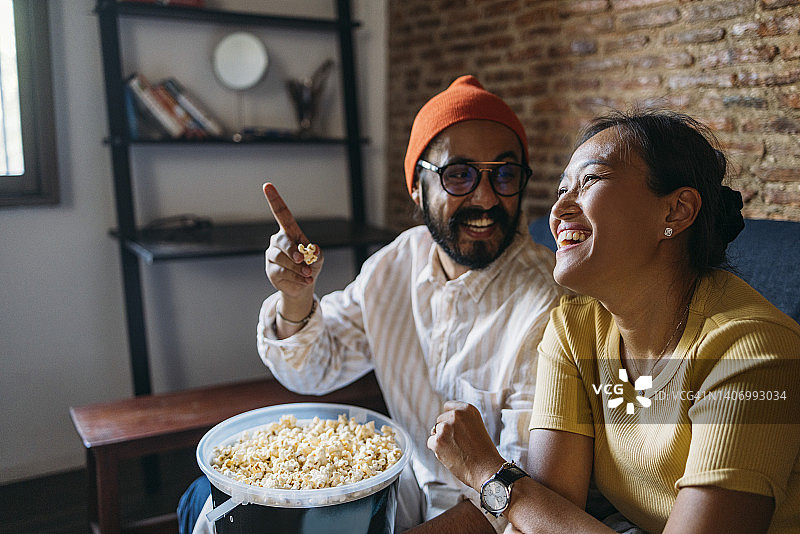 快乐的混血情侣在家吃爆米花图片素材
