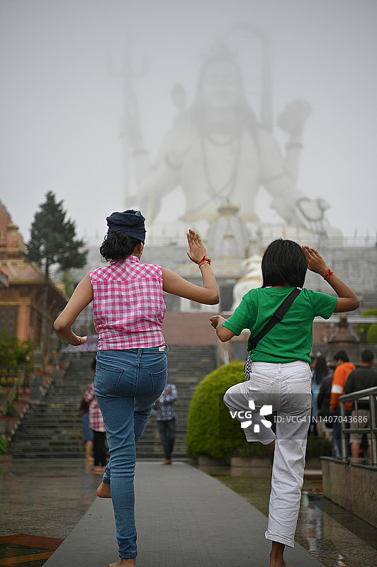 两个女孩向湿婆雕像祈祷的背影图片素材