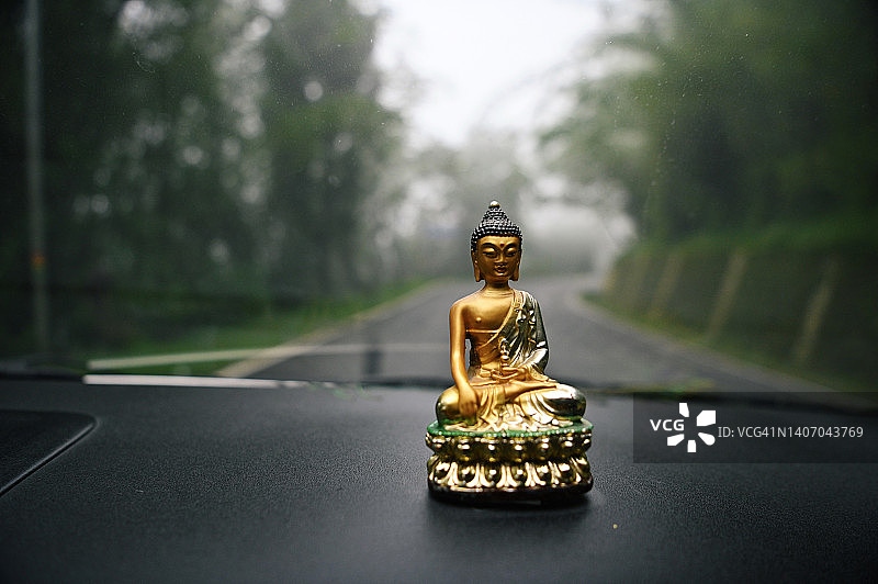 放在汽车仪表盘上的佛像图片素材