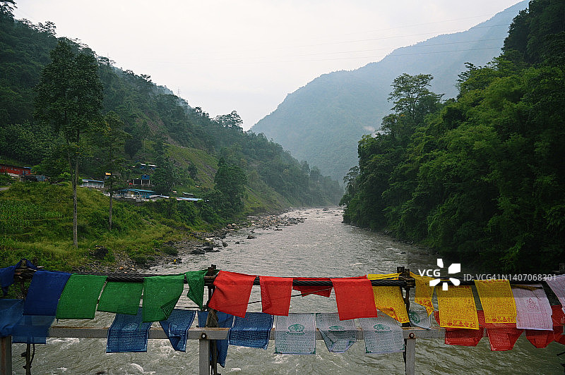 河流流淌于山间和祈祷旗帜之间图片素材
