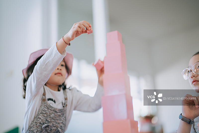 中国亚洲学龄前女孩在蒙特梭利教室完成积木塔的搭建图片素材