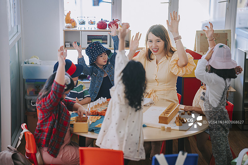 亚洲蒙特梭利幼儿园学生在课堂上举手回答问题图片素材