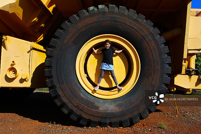 站在废弃大卡车轮胎上的澳大利亚女孩图片素材