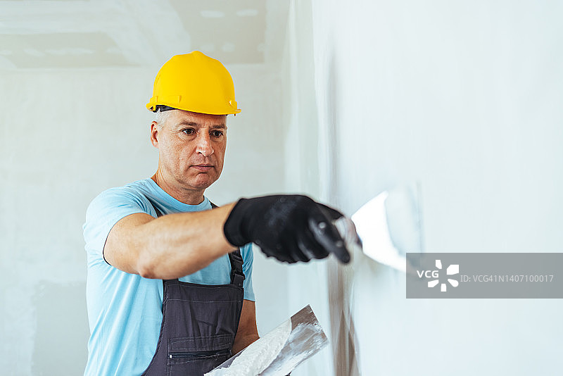 戴白色安全帽的施工人员正在粉刷墙壁图片素材