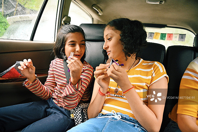两个女孩在车里旅行时吃巧克力图片素材