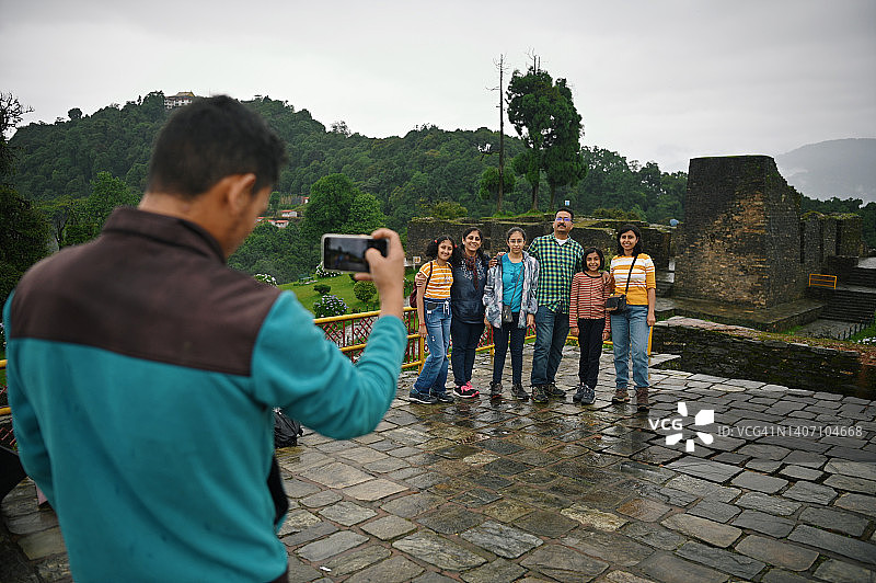 导游在古老的石头废墟上为游客家庭拍照图片素材