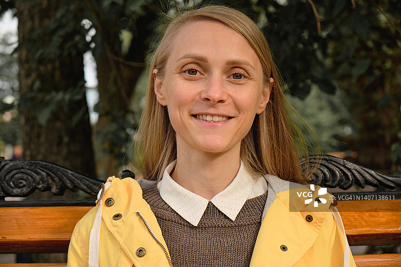 年轻漂亮的时尚女孩坐在公园长椅上，乐观自信的微笑图片素材