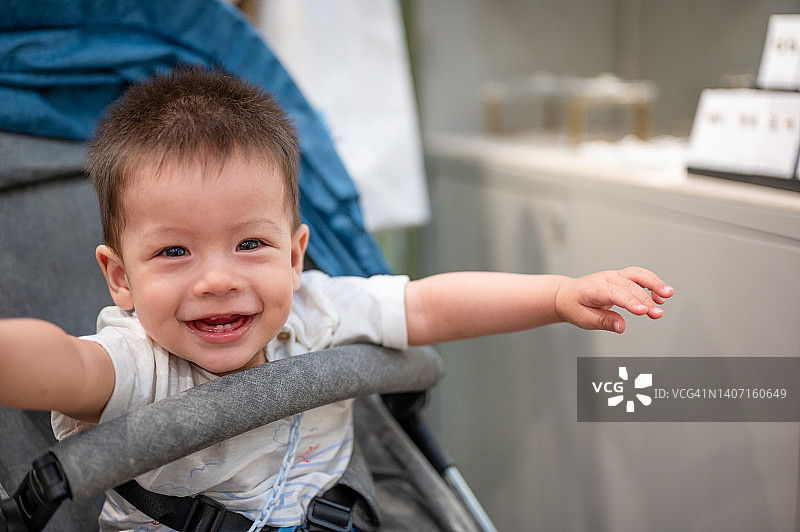 可爱的男婴在不知名的商场里坐在婴儿车里图片素材