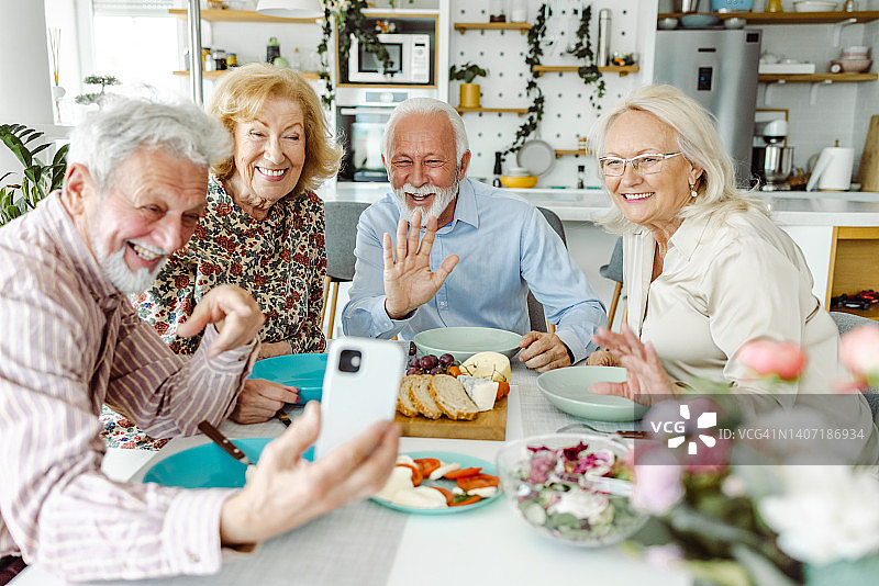 午餐时使用手机的年长朋友们图片素材