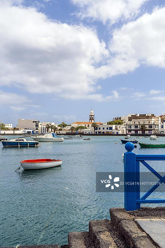 阿雷西费美丽的码头，加那利群岛兰萨罗特岛，西班牙，拥有历史建筑和蓝色水面上的船只图片素材