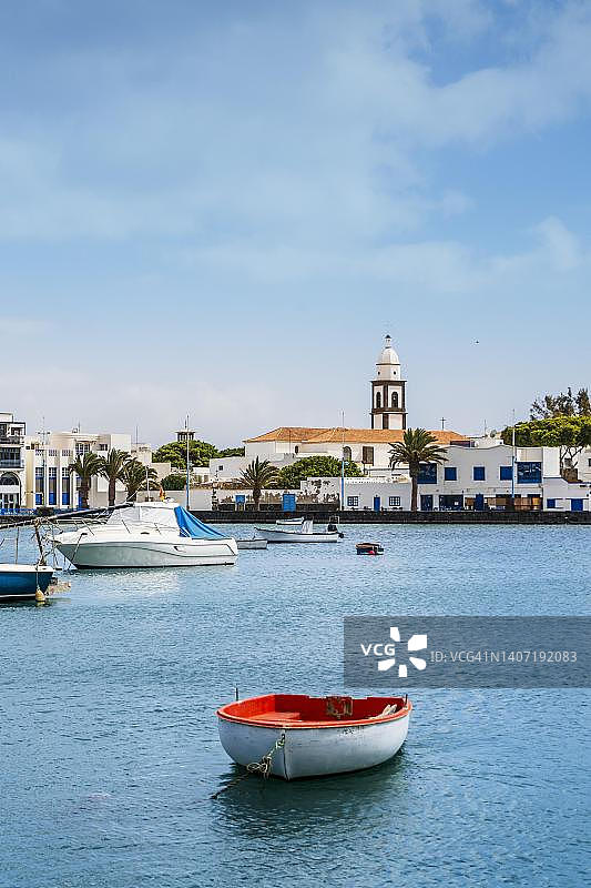阿雷西费美丽的码头，加那利群岛兰萨罗特岛，西班牙，拥有历史建筑和蓝色水面上的船只图片素材