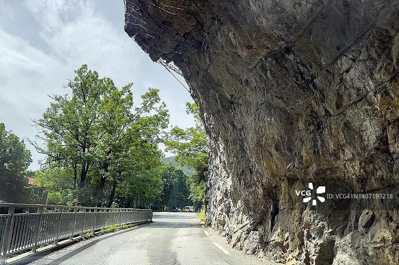 法国圣欧班峡谷狭窄道路上方的远眺悬垂岩面，有落石防护图片素材