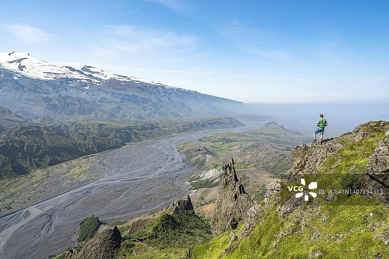 徒步者在岩石上，Valahnukur峰的岩层，Krossa冰川河流在山谷中，Eyjafjallajoekull冰川在后方，冰岛高地，南冰岛图片素材
