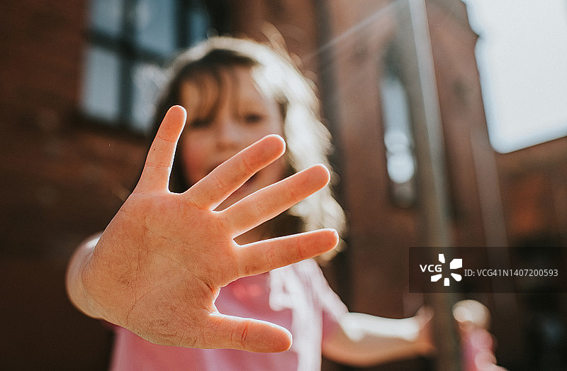聚焦孩子伸向相机的手，手指张开，小女孩保持柔焦图片素材