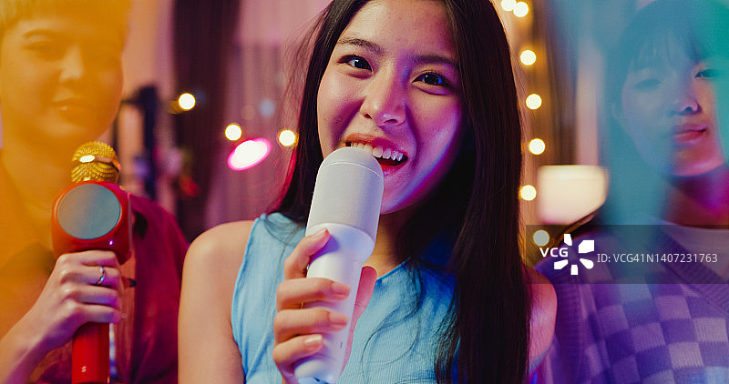特写：夜晚彩色家庭派对上，亚洲年轻女性朋友唱歌图片素材