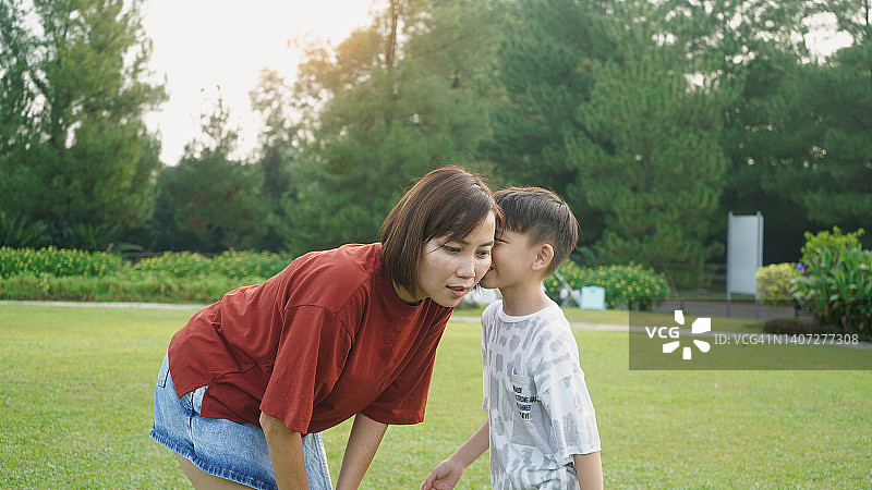 亚洲母亲和儿子耳语图片素材