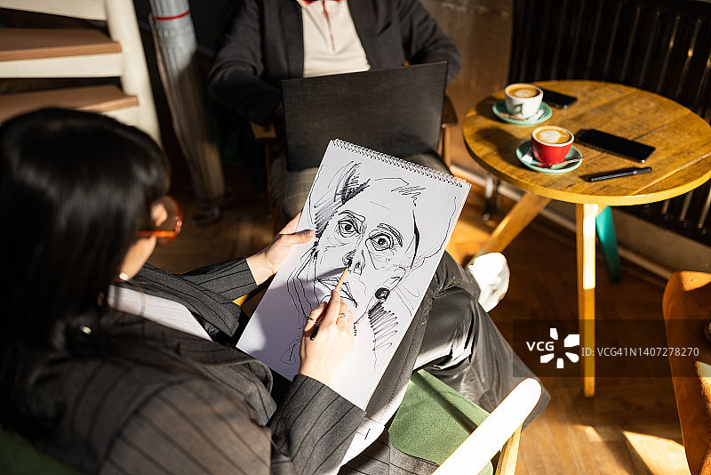 在咖啡店绘画的匿名女子图片素材