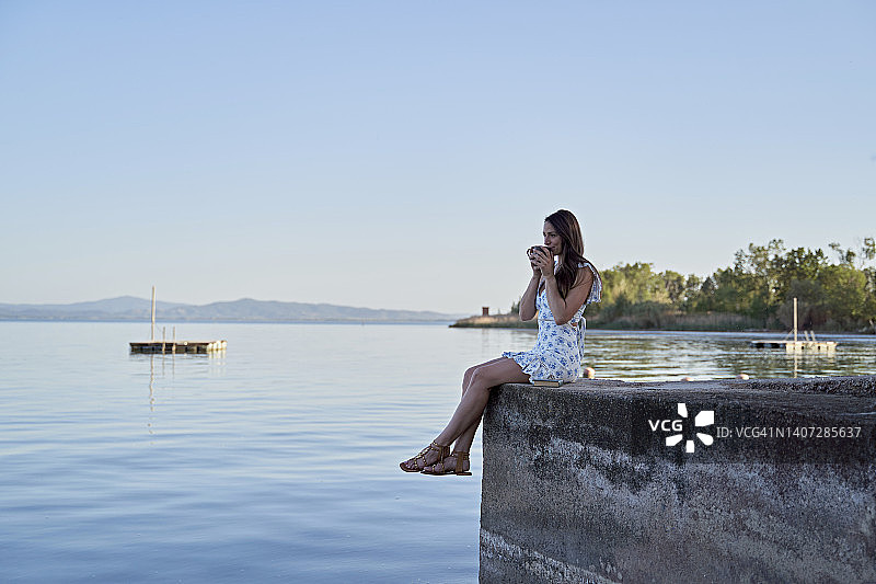 女人在湖边码头上喝咖啡图片素材