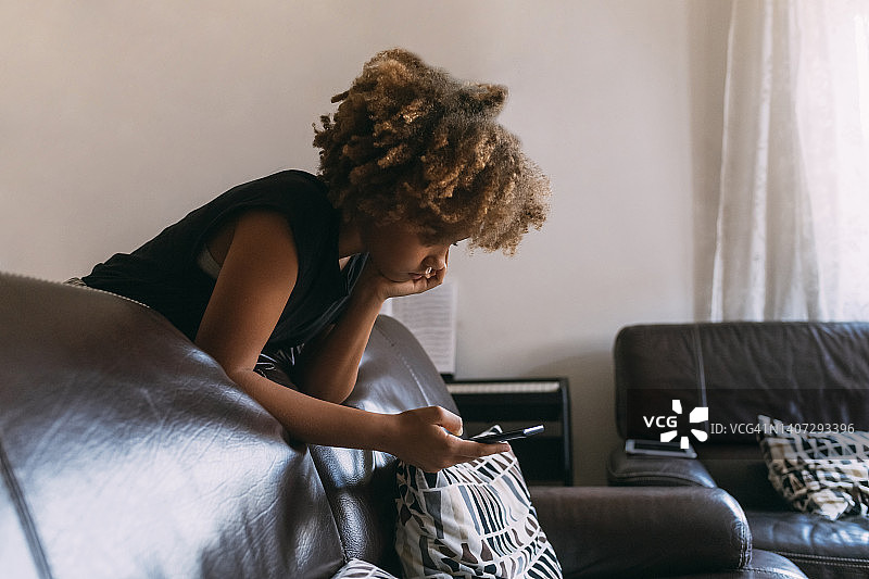 女孩在家靠在沙发上使用智能手机图片素材
