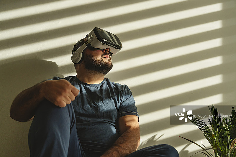 在家中墙前戴VR模拟器的男人图片素材