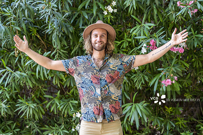 微笑的男人站在植物前，张开双臂图片素材