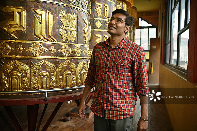 男人站在巨大的转经筒旁图片素材