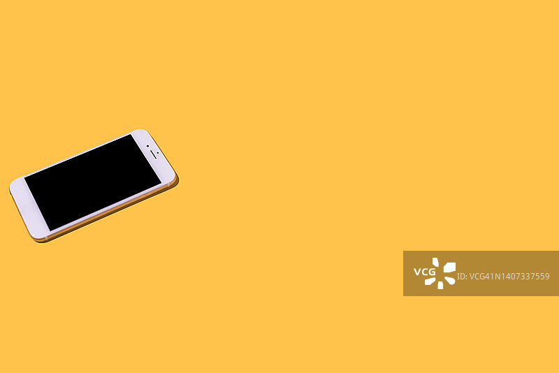 黄色背景上的白色手机。智能手机、手机、短信、消息、娱乐、通话、对话、互联网、连接的概念图片素材