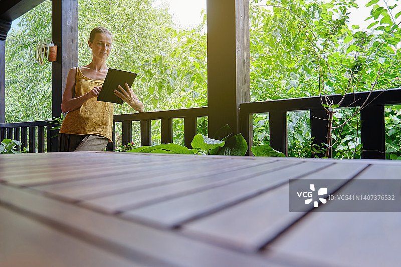 中年妇女度假时在阳台上查阅平板电脑图片素材