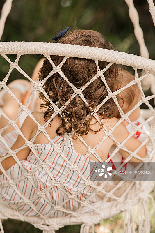 6个月大的男婴和3岁的姐姐在波西米亚风悬挂椅上庆祝7月4日图片素材