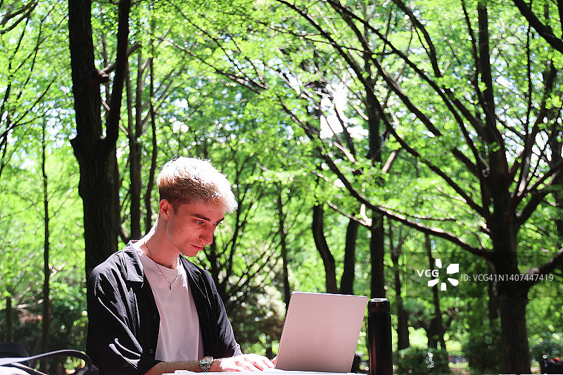 年轻男人在户外使用笔记本电脑工作图片素材