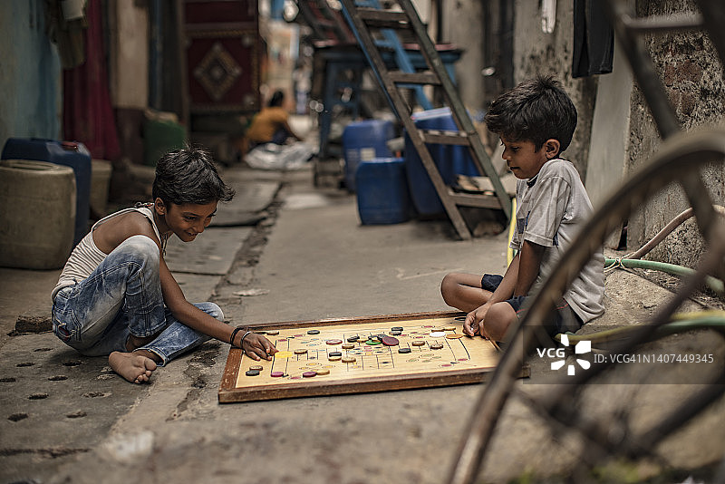 两个男孩在街上玩卡罗姆棋的侧面照图片素材