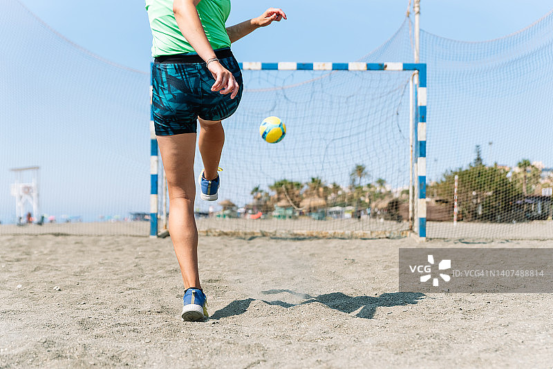 女子在沙滩足球场上踢球图片素材