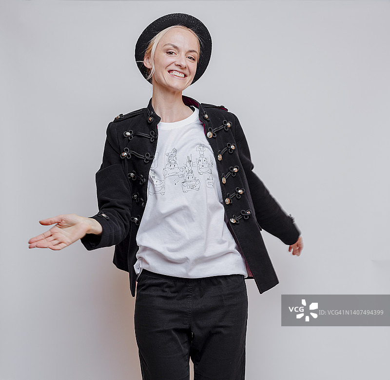 金发女子身穿黑色夹克和裤子站在工作室里图片素材