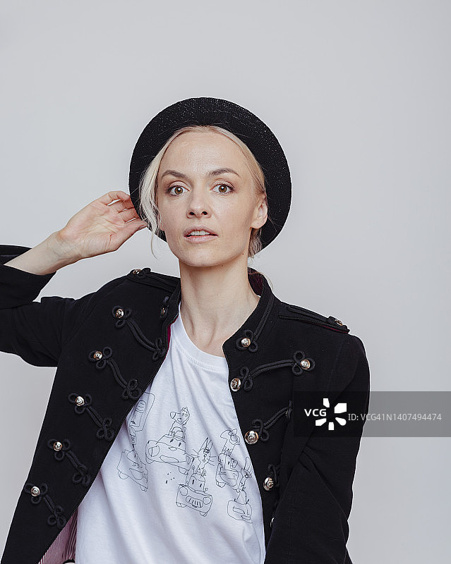 成年金发女性在工作室。黑色纽扣夹克，白色T恤上有图画图片素材