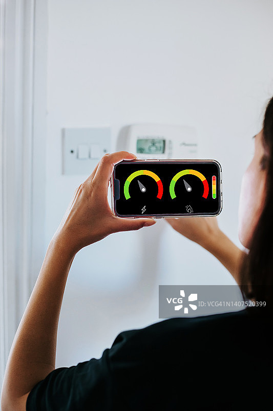 女人在客厅里拿着智能电能表测量能源效率的特写图片素材