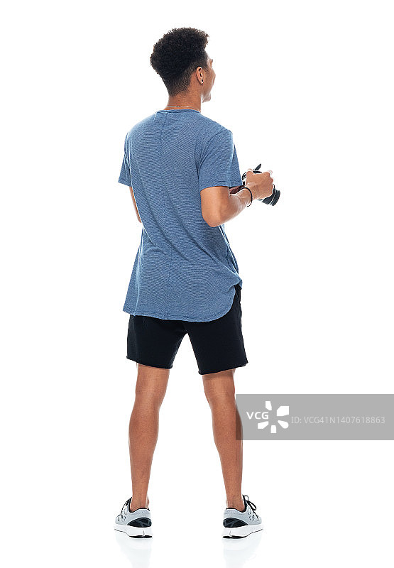 站在白色背景前，穿着运动鞋，手持相机的非洲裔男摄影师图片素材