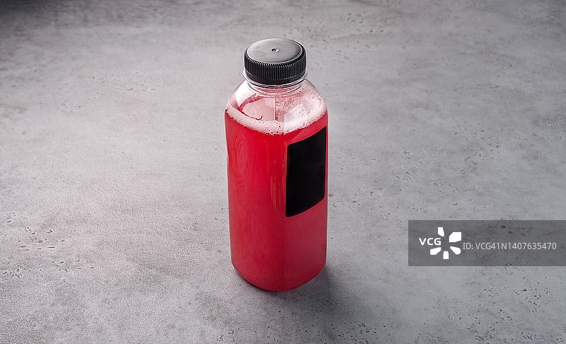 灰色背景上的透明塑料瓶装蔓越莓果汁图片素材