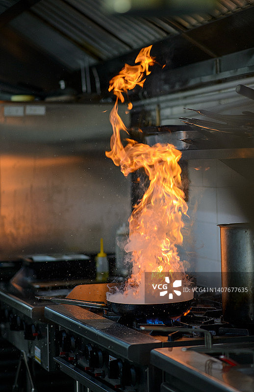 商业厨房中使用平底锅烹饪的火焰餐图片素材