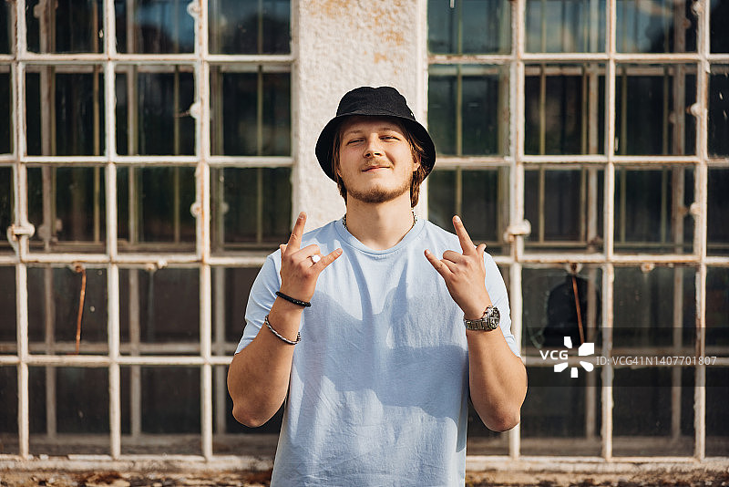 摇滚手势的微笑年轻男子趣味写真图片素材
