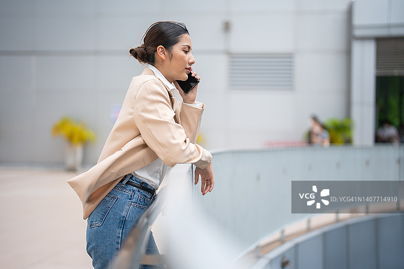 在户外使用智能手机的年轻亚裔女性图片素材