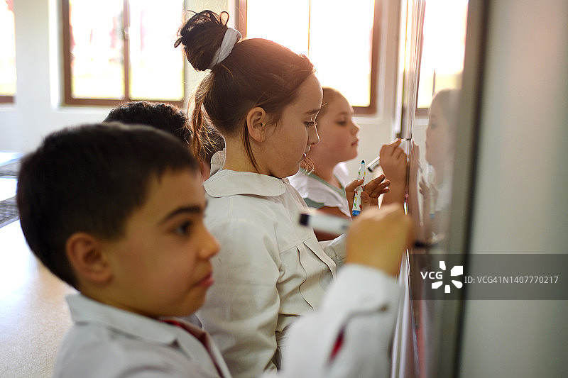 孩子们在学校的黑板上写字图片素材