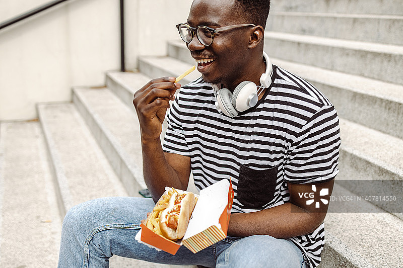 年轻的非裔美国男子在户外吃热狗图片素材