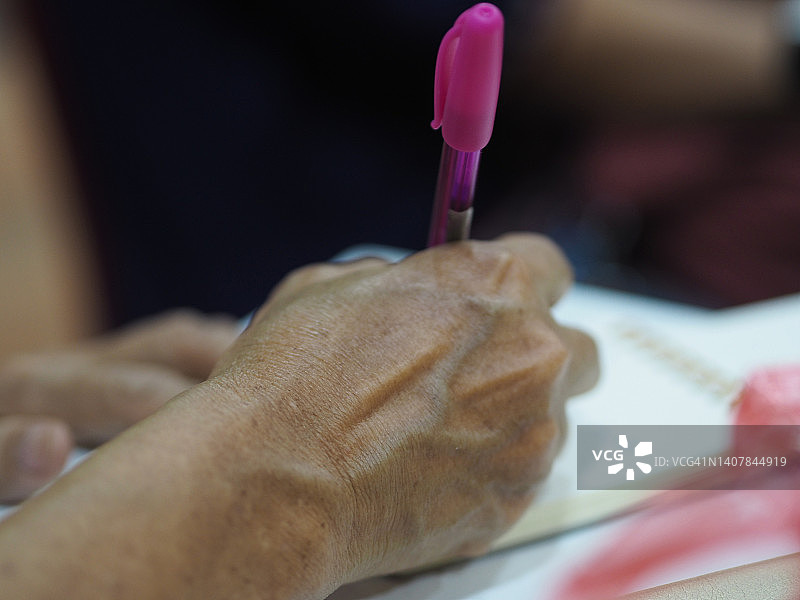 手握钢笔在纸上写字图片素材