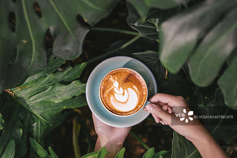 亚洲女性手持热咖啡拿铁图片素材